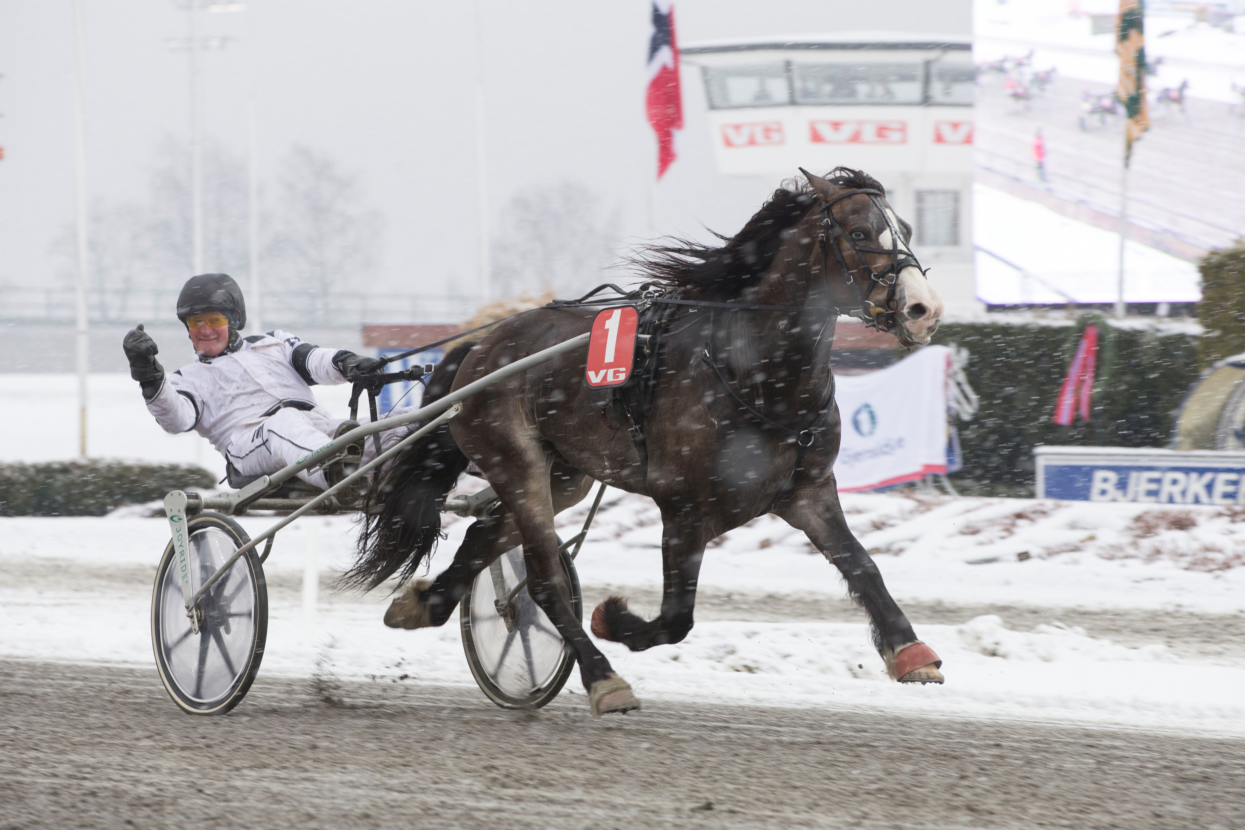 Travsport vinterstid gir minst like stor glede som ellers i året. Den glade amatør Henrik Kulblik viser med all tydelighet dette når han her i vinterskrud "oppløpsdefilerer" med Finnskog Lux. Foto: Hesteguiden.com
